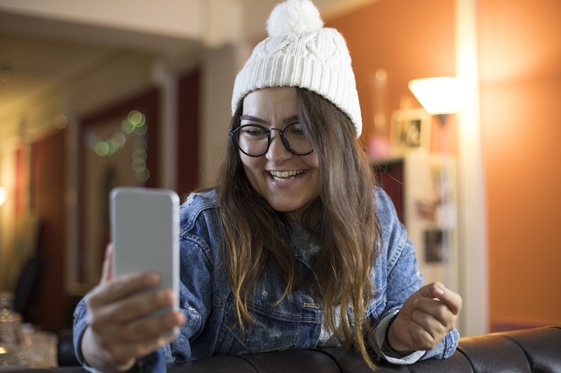 Happy young woman taking selfie video at workplace.