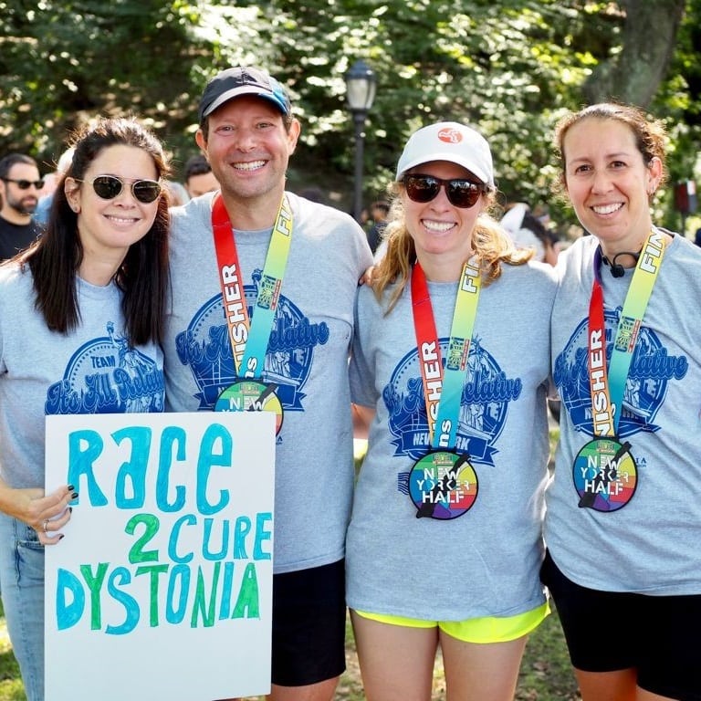 Four smiling people in running gear wearing race medals.