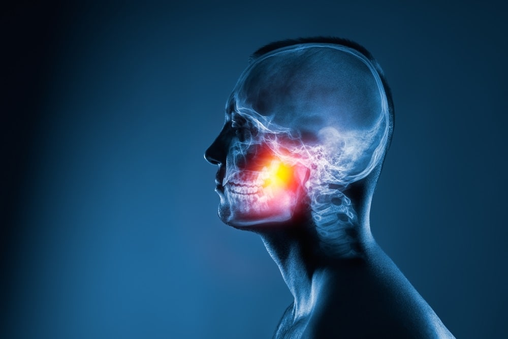 Semi-transparent profile of human head and neck with jaw area illuminated against dark background..