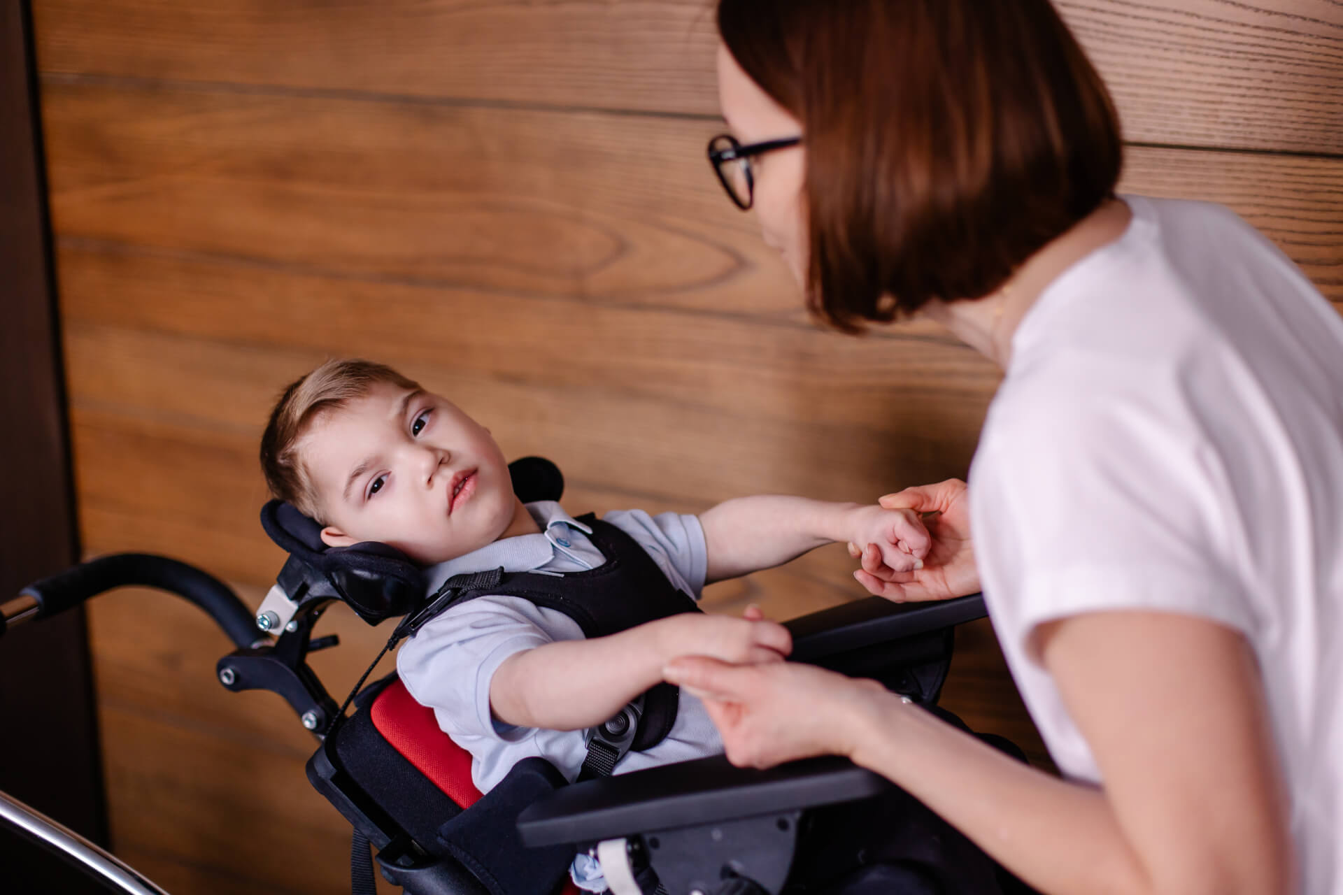 Boy in a special wheelchair with a rehabilitation therapist.