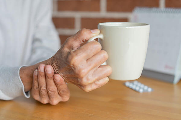 Person holding their wrist and a coffee cup.
